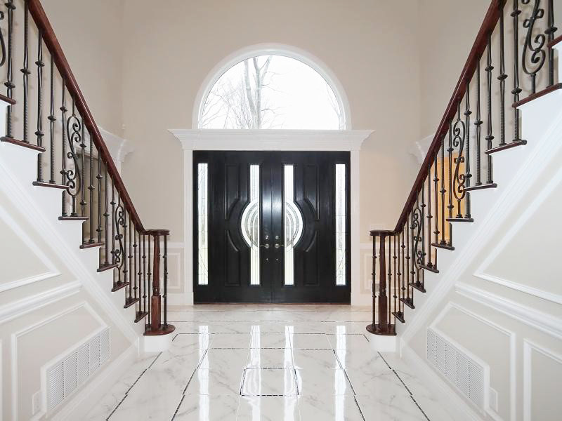 This is an example of a large traditional foyer in New York with beige walls, marble floors, a double front door and a black front door.