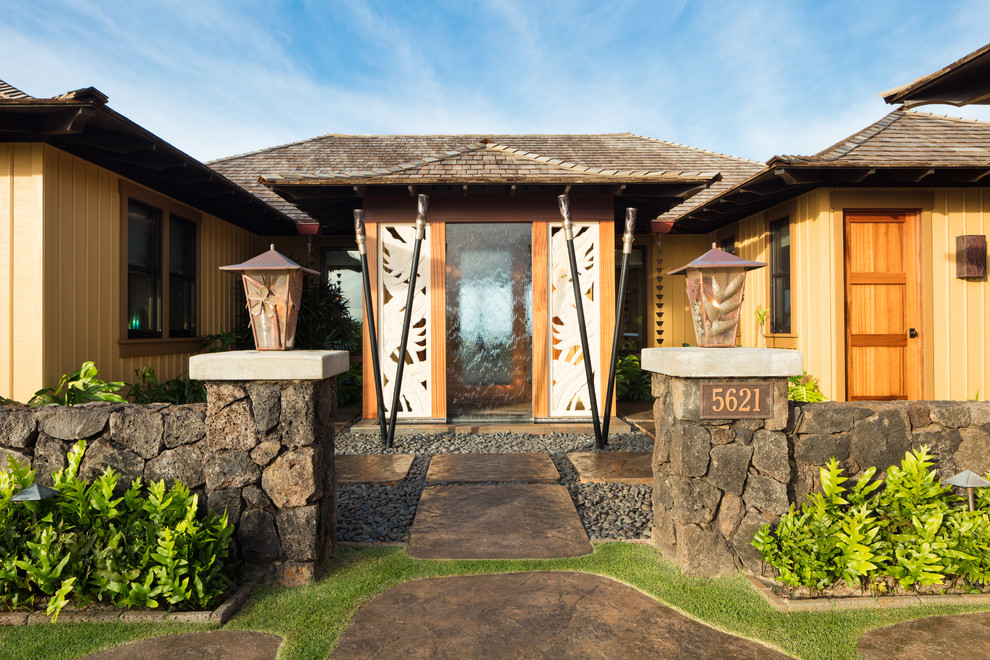 This is an example of a mid-sized tropical front door in Hawaii with yellow walls, concrete floors, a double front door, a medium wood front door and grey floor.