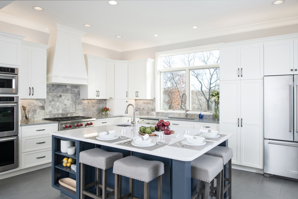 This is an example of a large transitional l-shaped kitchen in Kansas City with a single-bowl sink, shaker cabinets, white cabinets, quartz benchtops, grey splashback, stone tile splashback, stainless steel appliances, porcelain floors, with island, grey floor and white benchtop.
