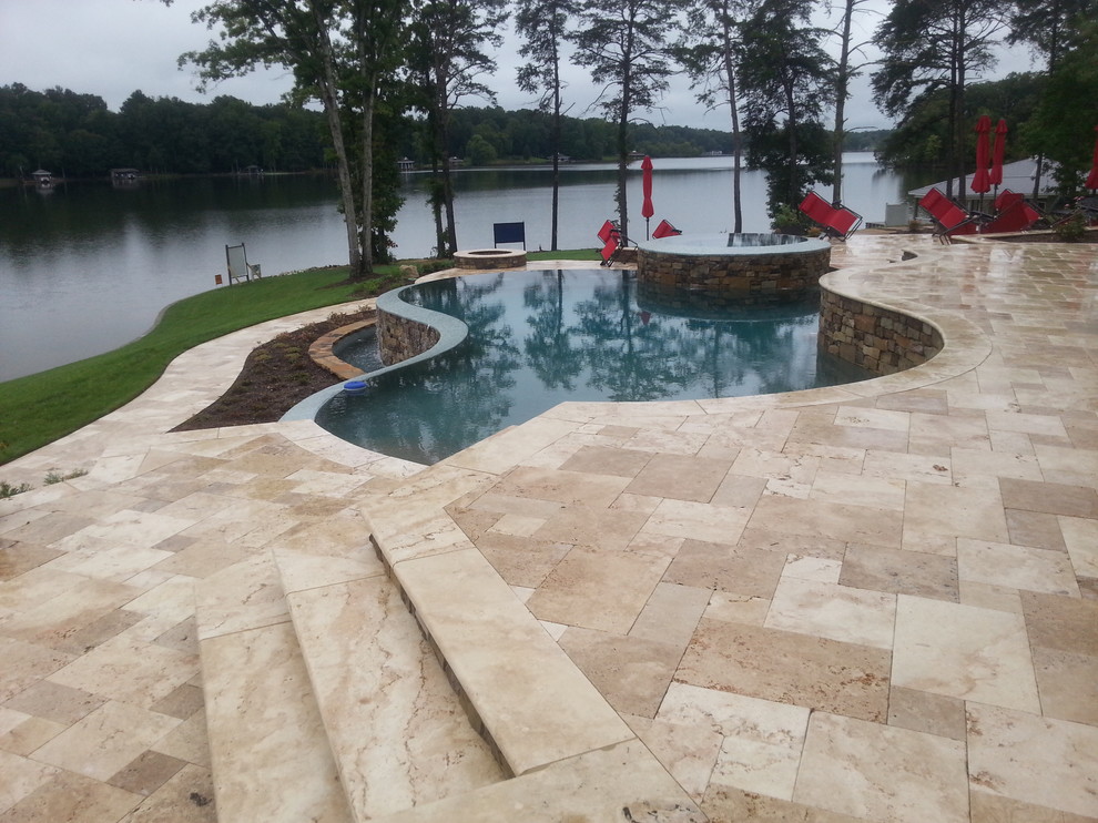 Example of a large transitional backyard stone and custom-shaped infinity hot tub design