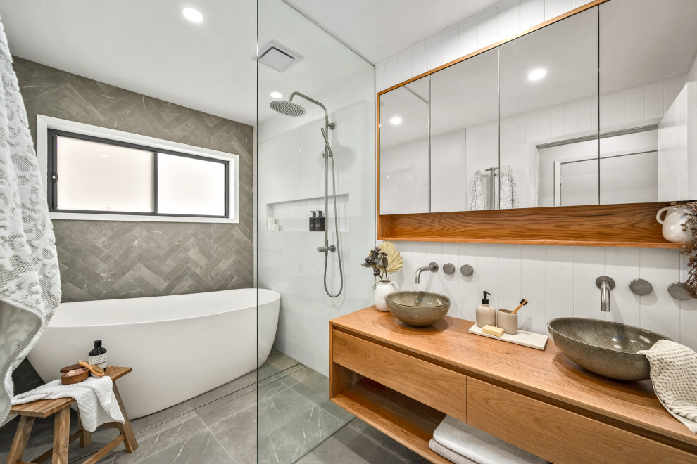 Imagen de cuarto de baño principal, doble y flotante actual de tamaño medio con puertas de armario de madera clara, ducha abierta, lavabo sobreencimera, ducha abierta y hornacina