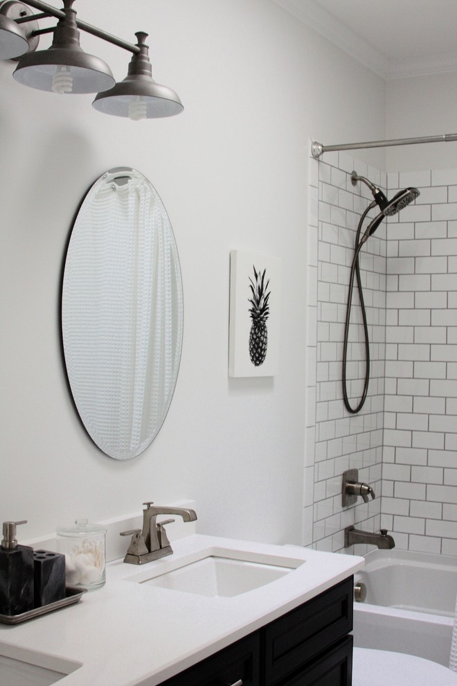 This is an example of a small transitional bathroom in Raleigh with a drop-in tub, a shower/bathtub combo, a one-piece toilet, white walls, marble floors, grey floor and a shower curtain.