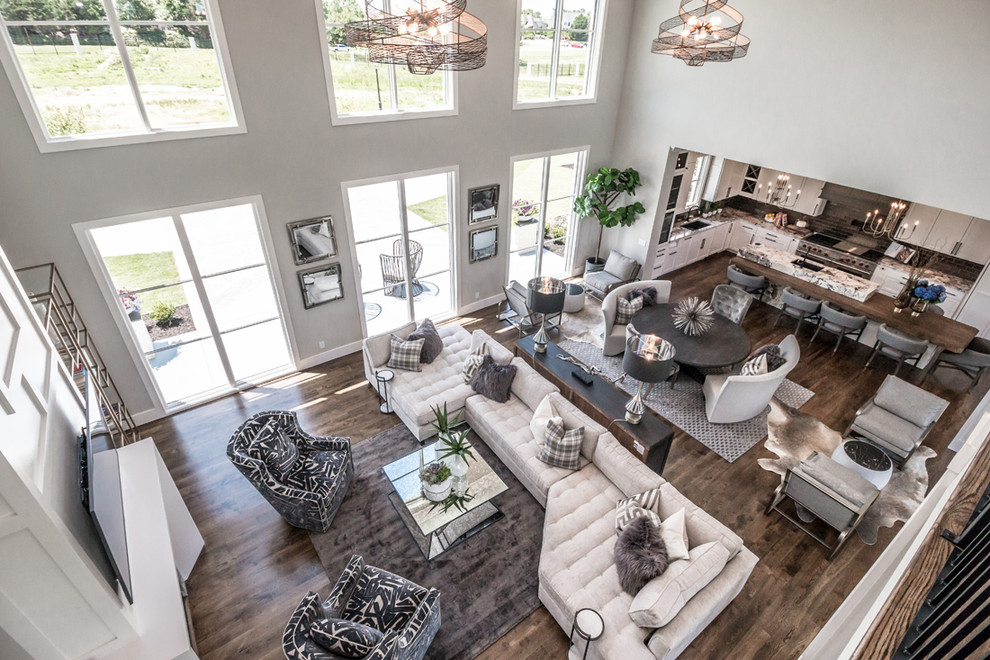 Inspiration for an expansive transitional open concept living room in Other with grey walls, medium hardwood floors, a two-sided fireplace, a tile fireplace surround, a wall-mounted tv and brown floor.