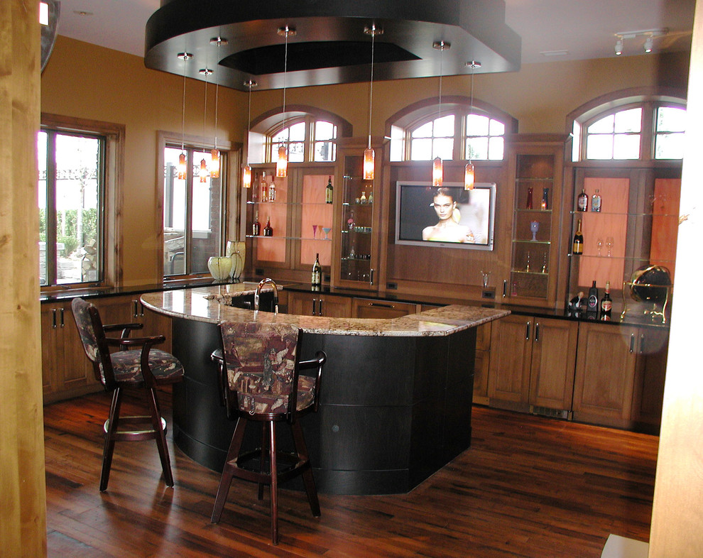 Inspiration for a large traditional l-shaped seated home bar in Detroit with dark wood cabinets, granite benchtops, recessed-panel cabinets, brown splashback, timber splashback and dark hardwood floors.