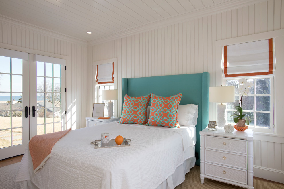Photo of a beach style bedroom in Boston with white walls, medium hardwood floors and brown floor.