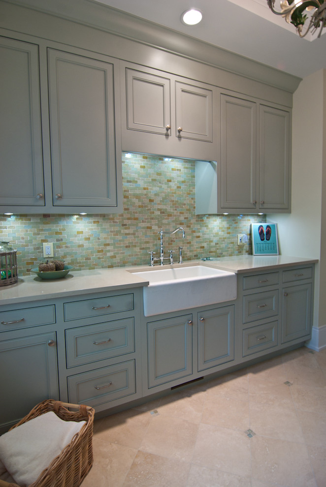 Photo of a large galley dedicated laundry room in Grand Rapids with a farmhouse sink, recessed-panel cabinets, green cabinets, quartz benchtops, blue splashback, mosaic tile splashback, yellow walls, porcelain floors, an integrated washer and dryer, beige floor, beige benchtop and timber.