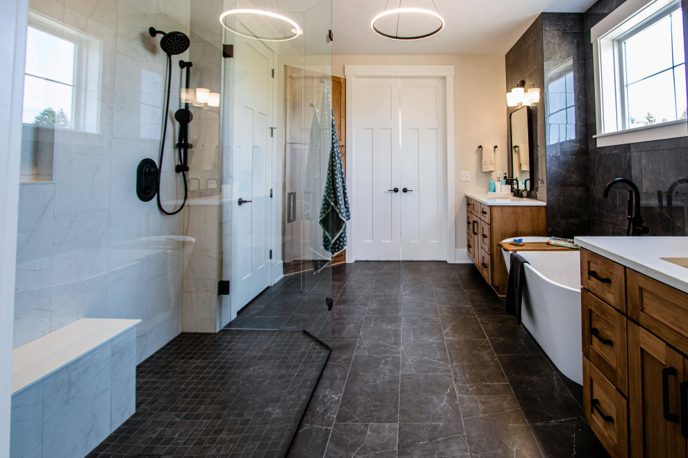 This is an example of a mid-sized transitional master bathroom in Cleveland with flat-panel cabinets, medium wood cabinets, a freestanding tub, a curbless shower, a two-piece toilet, black tile, cement tile, black walls, an undermount sink, engineered quartz benchtops, a hinged shower door, white benchtops, a single vanity and a built-in vanity.