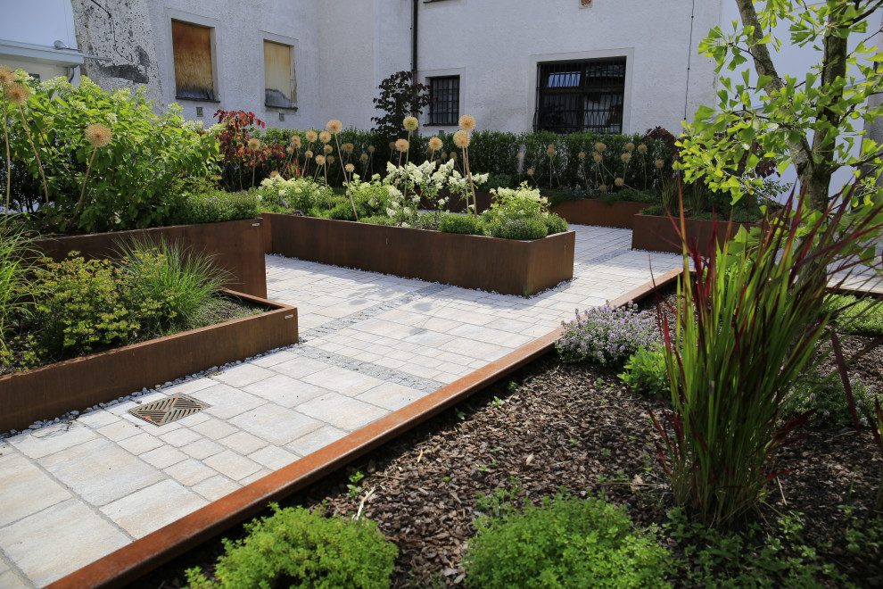 Design ideas for a large contemporary rooftop full sun garden in Munich with with flowerbed and natural stone pavers.