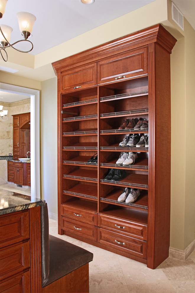 Large traditional walk-in wardrobe in Chicago with raised-panel cabinets, medium wood cabinets and travertine floors.