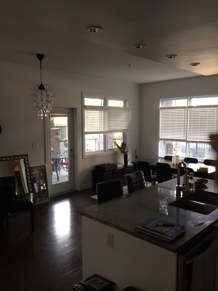 Inspiration for a mid-sized transitional l-shaped dark wood floor eat-in kitchen remodel in Edmonton with an undermount sink, flat-panel cabinets, white cabinets, granite countertops, gray backsplash, ceramic backsplash, stainless steel appliances and an island