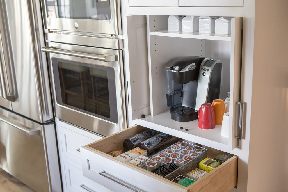 Example of a mid-sized transitional u-shaped light wood floor and brown floor kitchen pantry design in Baltimore with an undermount sink, shaker cabinets, white cabinets, marble countertops, gray backsplash, marble backsplash, stainless steel appliances and an island