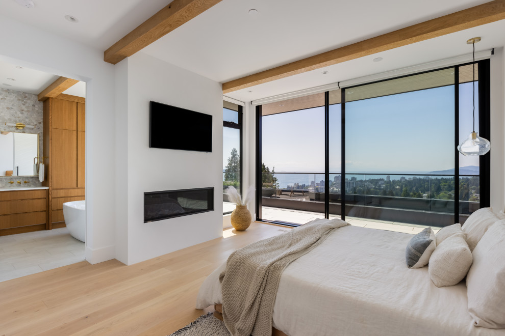 Inspiration for a medium sized contemporary bedroom in Vancouver with light hardwood flooring, a standard fireplace, beige floors and exposed beams.