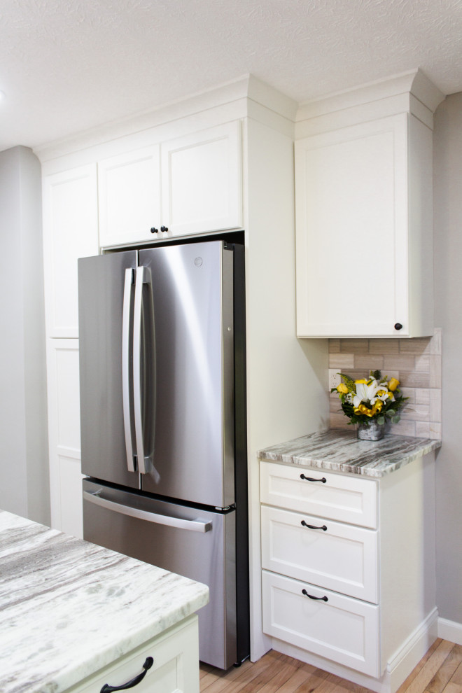 Inspiration for a transitional l-shaped light wood floor and beige floor kitchen remodel in Columbus with an undermount sink, white cabinets, gray backsplash, an island and gray countertops