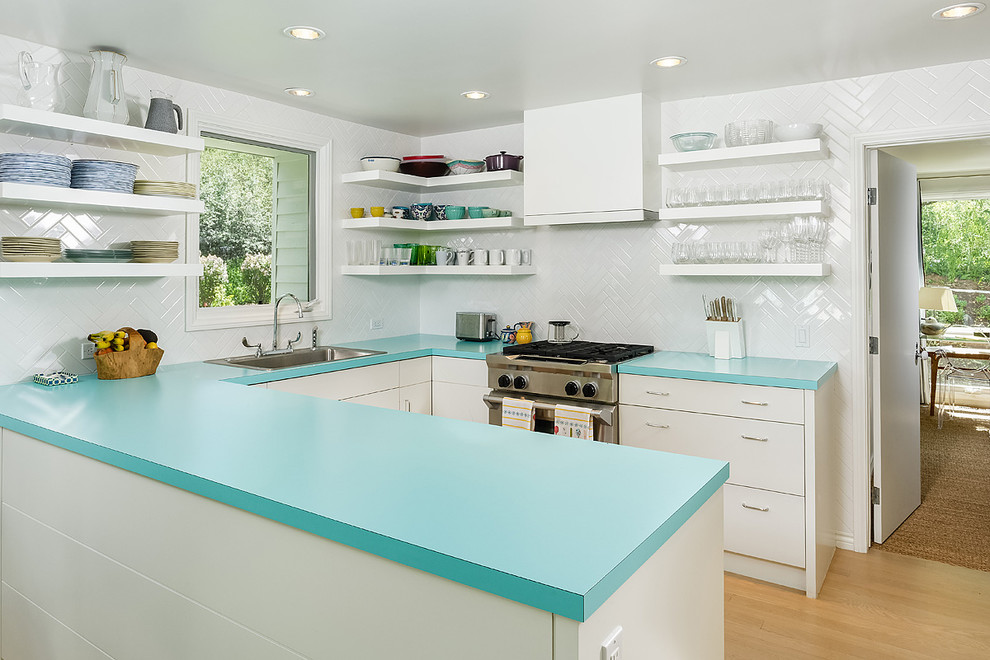 Design ideas for a small transitional u-shaped kitchen in Denver with a drop-in sink, flat-panel cabinets, white cabinets, laminate benchtops, white splashback, subway tile splashback, stainless steel appliances, medium hardwood floors, a peninsula and turquoise benchtop.