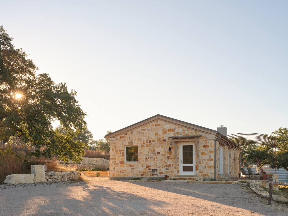 Mid-sized farmhouse one-story stone gable roof idea in Austin with a tile roof and a gray roof