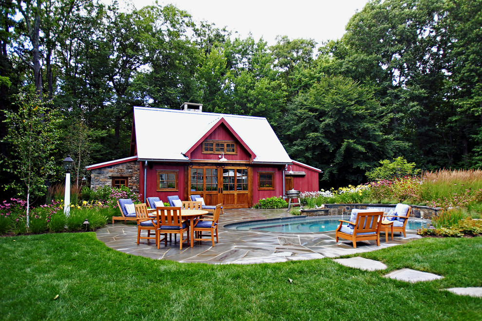 Photo of a mid-sized country backyard round lap pool in New York with a pool house and natural stone pavers.
