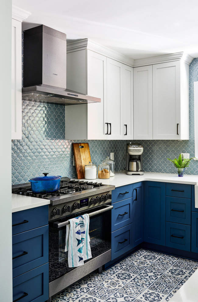 Example of a transitional l-shaped blue floor eat-in kitchen design in DC Metro with a farmhouse sink, blue cabinets, blue backsplash, black appliances, an island and white countertops
