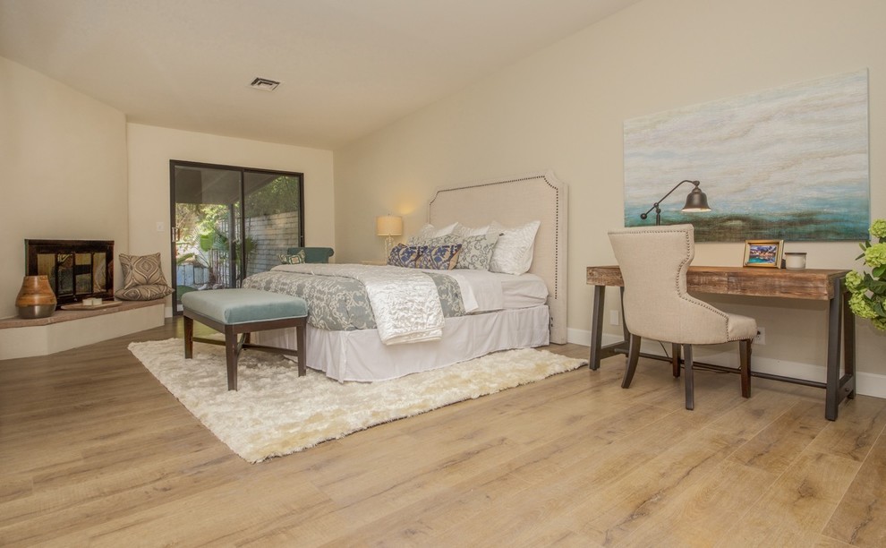 Mid-sized country master bedroom in Las Vegas with beige walls, laminate floors, a corner fireplace, a plaster fireplace surround and beige floor.
