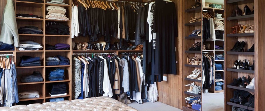 This is an example of a contemporary gender neutral walk-in wardrobe in London with open cabinets and dark wood cabinets.