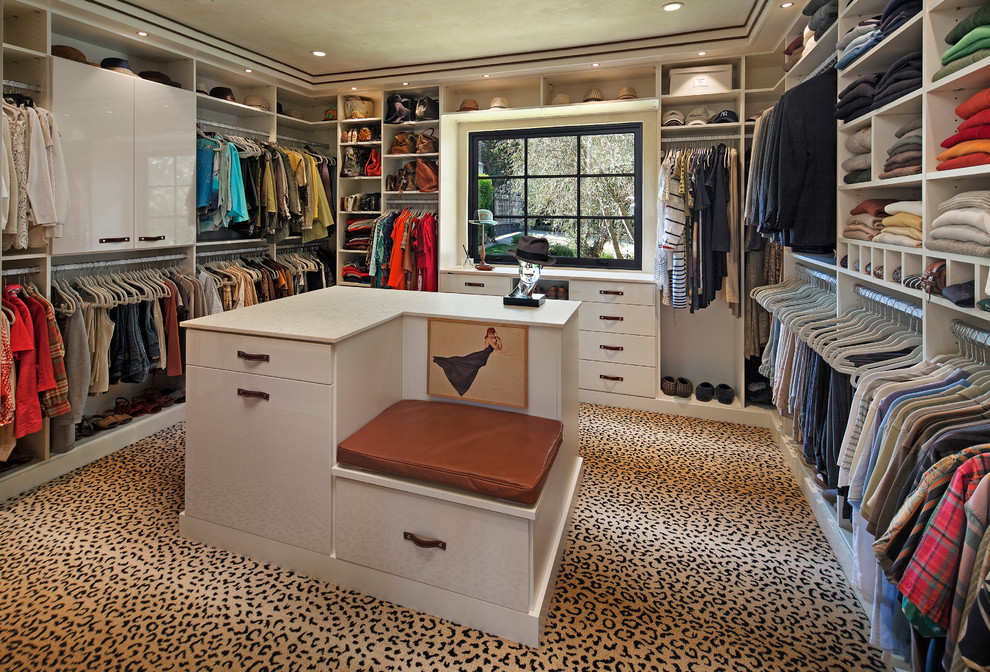 Inspiration for a large mediterranean women's walk-in wardrobe in Santa Barbara with flat-panel cabinets, white cabinets and carpet.