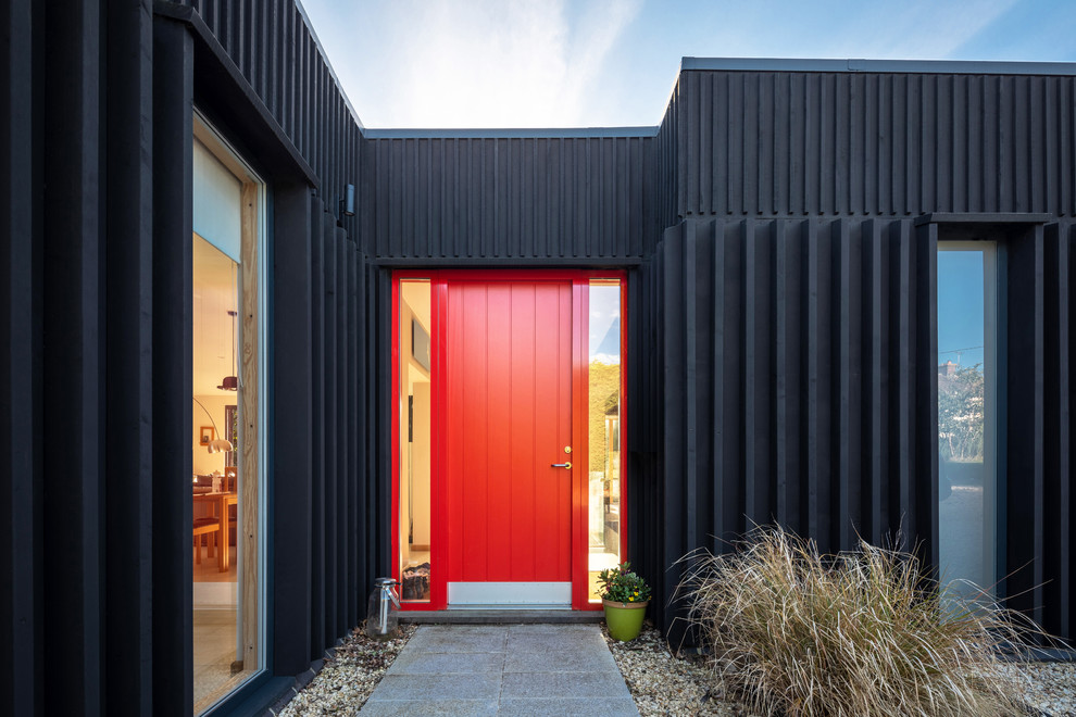 Photo of an industrial entryway in Oxfordshire with black walls, a single front door and a red front door.