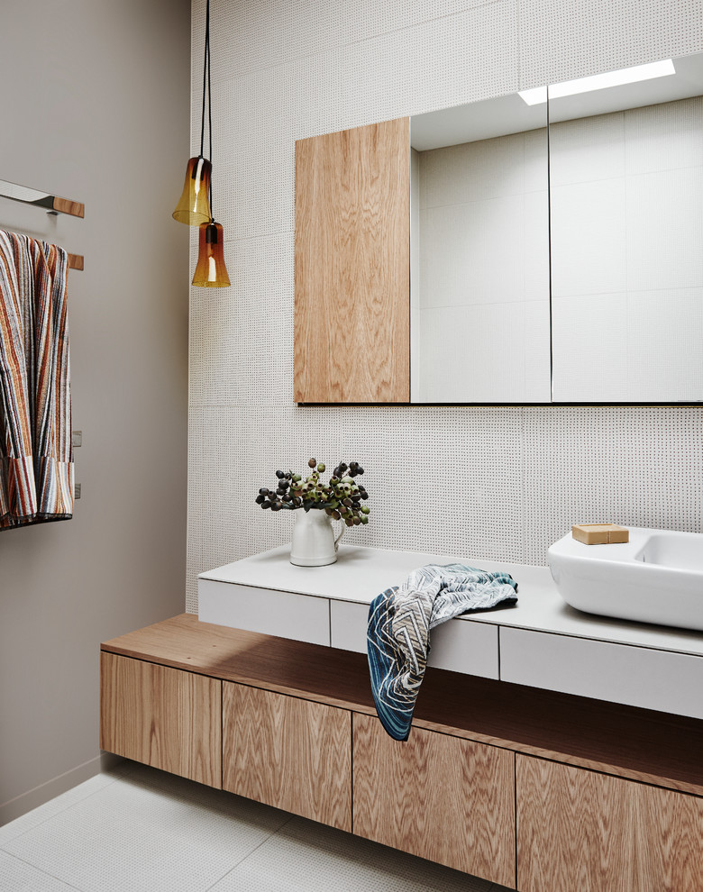 Design ideas for a contemporary bathroom in Wellington with flat-panel cabinets, medium wood cabinets, white tile, brown walls, a vessel sink, white floor and white benchtops.