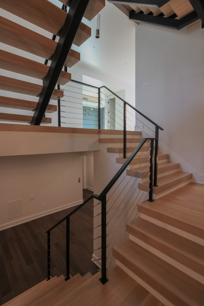 Пример оригинального дизайна: большая лестница на больцах в стиле фьюжн с деревянными ступенями, металлическими перилами и кирпичными стенами