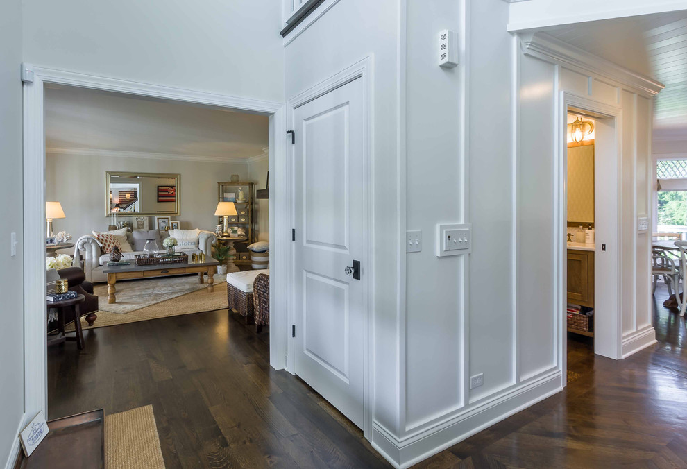 Photo of a mid-sized transitional foyer in Chicago with white walls, medium hardwood floors, a single front door, a dark wood front door, brown floor, wallpaper and decorative wall panelling.