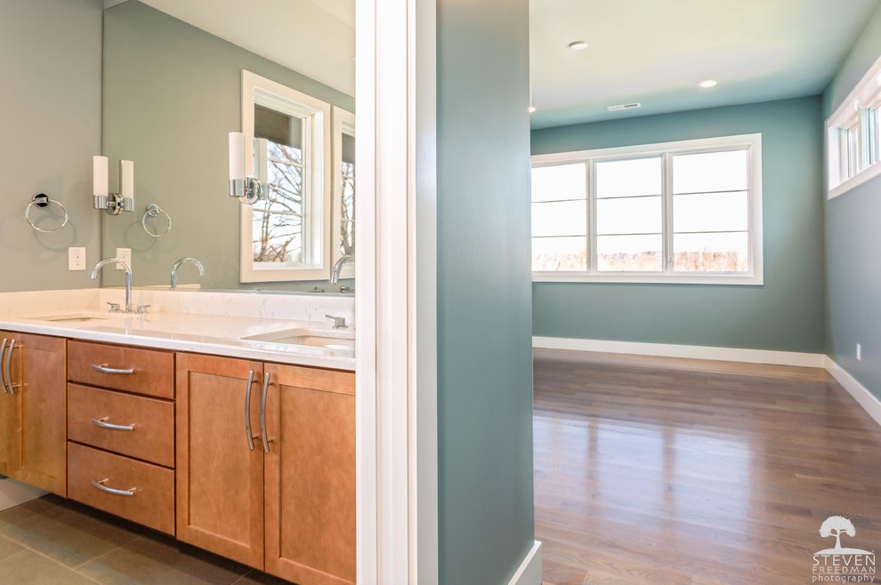 Minimalist home design photo with recessed-panel cabinets, light wood cabinets, blue walls, an undermount sink and quartz countertops