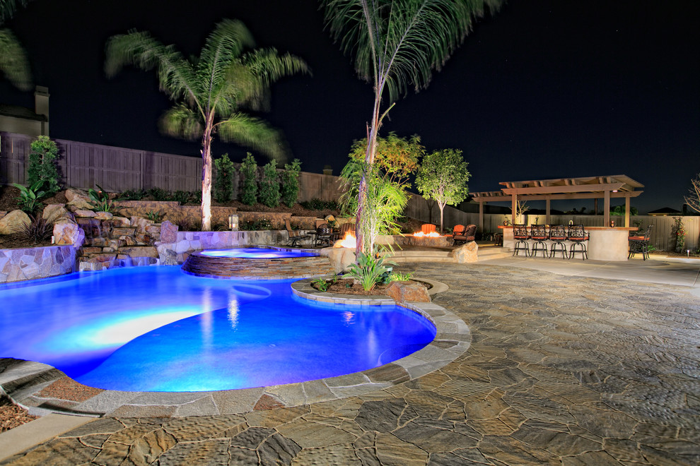 Expansive backyard custom-shaped natural pool in San Diego with concrete pavers.