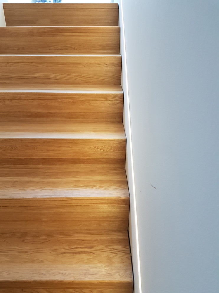 Photo of a large contemporary wood u-shaped staircase in Frankfurt with wood risers and wood railing.