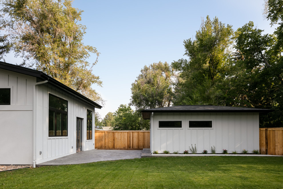 This is an example of a large and white modern bungalow brick detached house in Denver with a hip roof, a shingle roof, a grey roof and board and batten cladding.