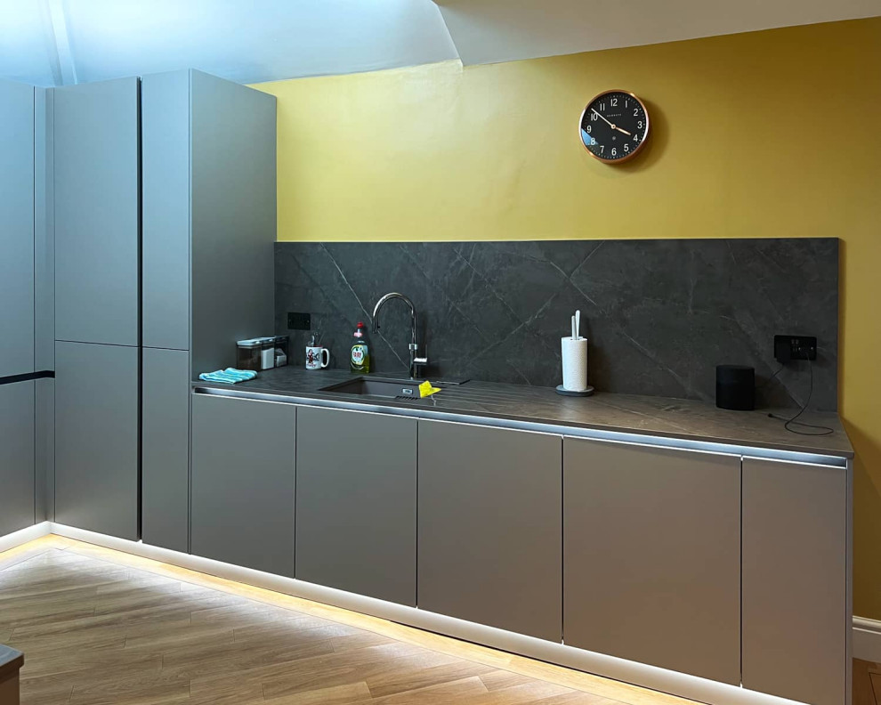 This is an example of a mid-sized contemporary u-shaped separate kitchen in London with flat-panel cabinets, grey cabinets, quartzite benchtops, light hardwood floors and grey benchtop.