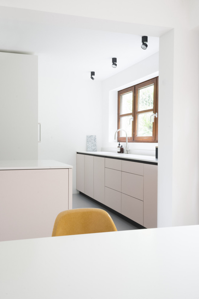 Photo of a large modern galley eat-in kitchen in Berlin with a drop-in sink, flat-panel cabinets, pink cabinets, quartz benchtops, white splashback, window splashback, panelled appliances, linoleum floors, with island, grey floor and white benchtop.