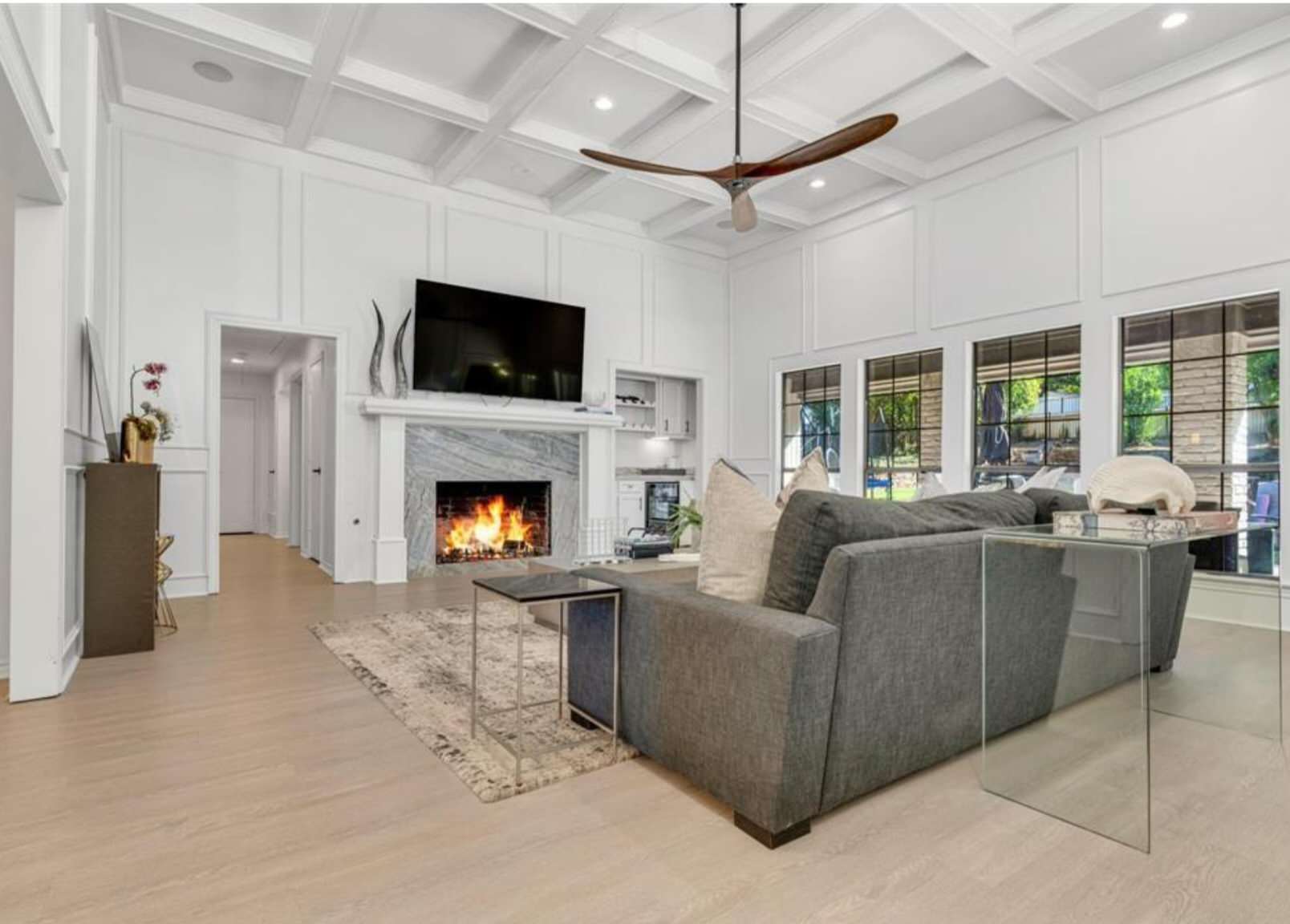 Inspiration for a large contemporary open concept vinyl floor, wood ceiling and wainscoting living room remodel in Dallas with white walls, a wood stove, a stone fireplace and a wall-mounted tv