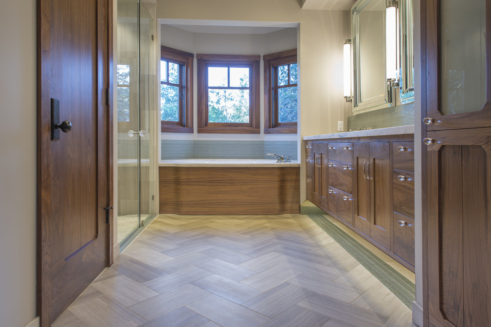 Design ideas for a transitional bathroom in San Francisco with an undermount sink, shaker cabinets, medium wood cabinets, an alcove tub, a one-piece toilet, green tile, glass tile, grey walls and travertine floors.