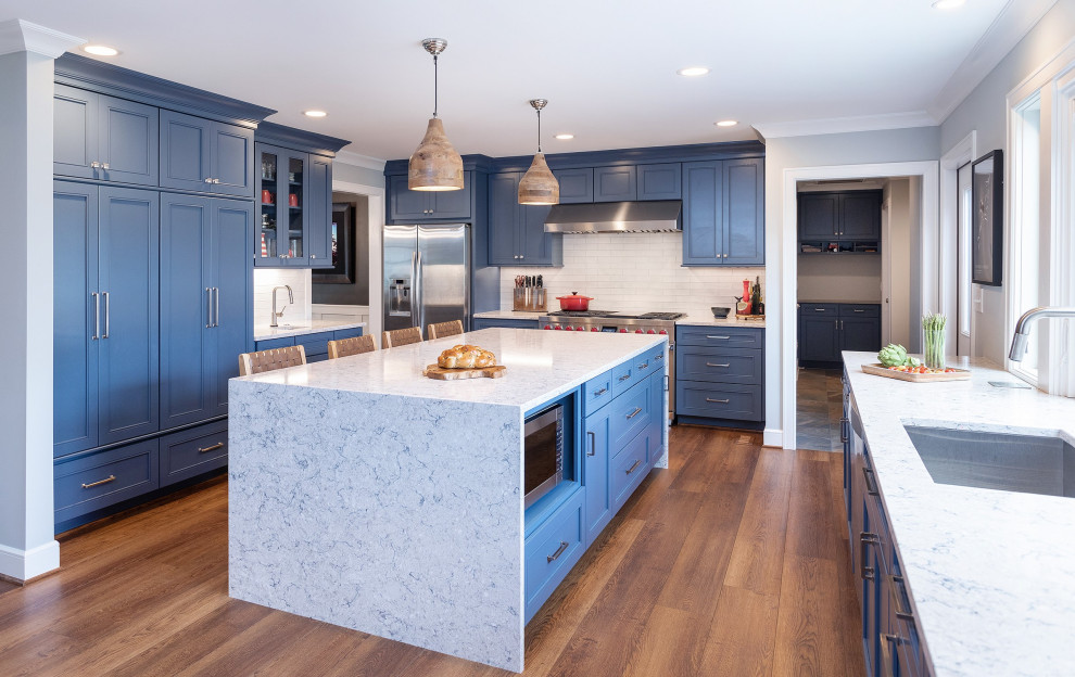 Example of a transitional vinyl floor and brown floor eat-in kitchen design in Raleigh with an undermount sink, recessed-panel cabinets, blue cabinets, quartz countertops, white backsplash, subway tile backsplash, an island and white countertops