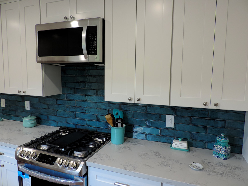 Design ideas for a small separate kitchen in Los Angeles with an undermount sink, shaker cabinets, white cabinets, quartz benchtops, blue splashback, porcelain splashback, stainless steel appliances, porcelain floors, orange floor and white benchtop.