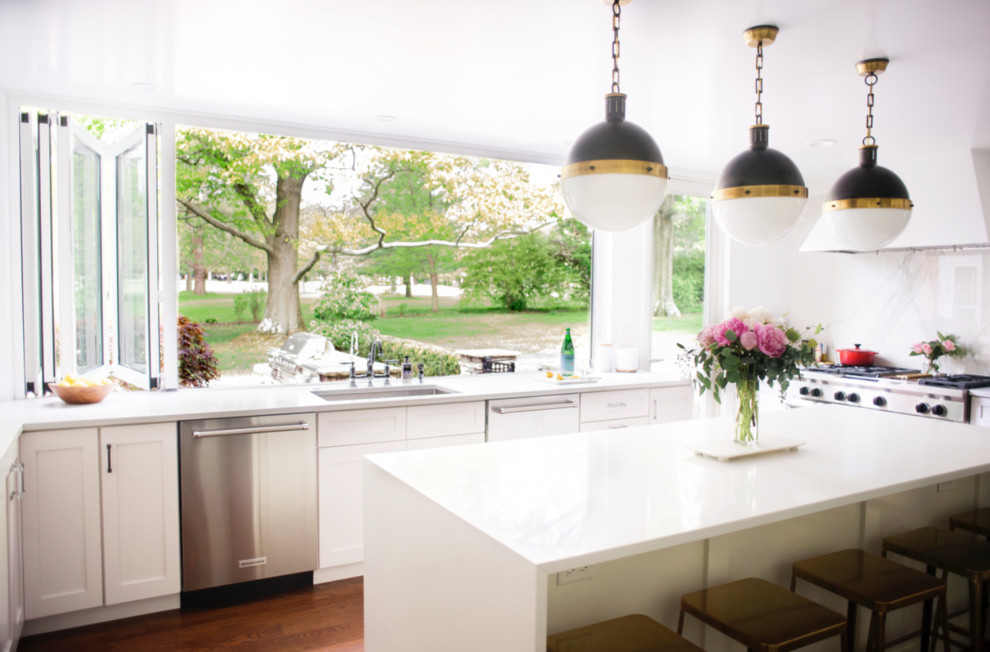 Inspiration for a transitional dark wood floor and brown floor enclosed kitchen remodel with an undermount sink, shaker cabinets, white cabinets, quartz countertops, white backsplash, stone slab backsplash, stainless steel appliances and an island