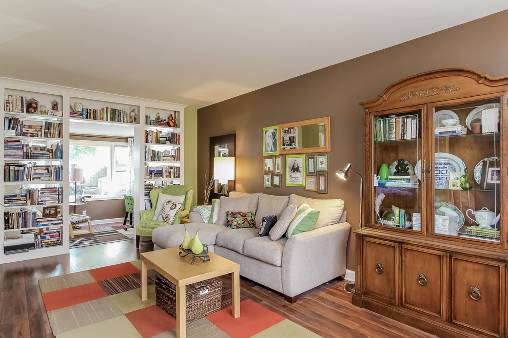 This is an example of a mid-sized eclectic open concept living room in Grand Rapids with green walls, dark hardwood floors and a freestanding tv.