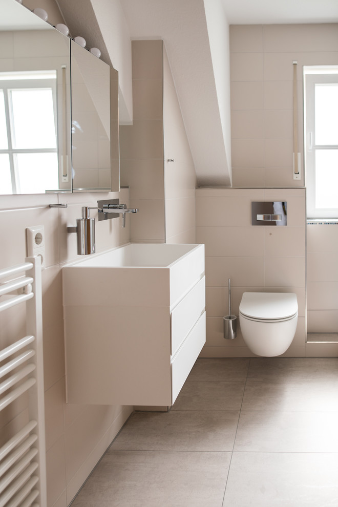 Mittelgroße Moderne Gästetoilette mit weißen Schränken, Wandtoilette, integriertem Waschbecken, flächenbündigen Schrankfronten, beigen Fliesen, weißer Wandfarbe und beigem Boden in Sonstige