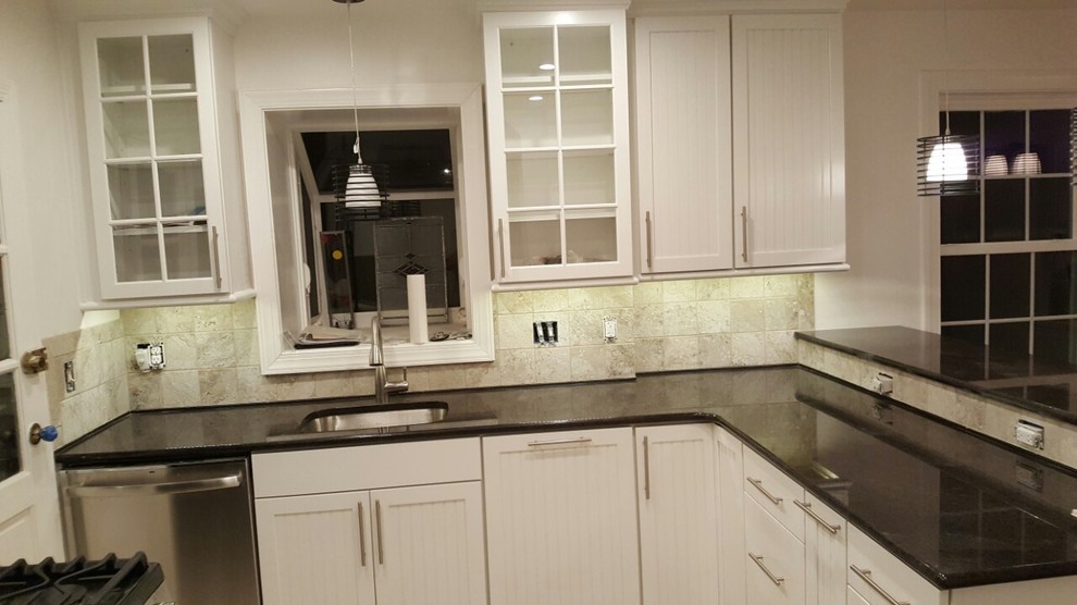 Mid-sized transitional u-shaped porcelain tile and beige floor enclosed kitchen photo in DC Metro with an undermount sink, recessed-panel cabinets, white cabinets, granite countertops, beige backsplash, travertine backsplash, stainless steel appliances, a peninsula and black countertops