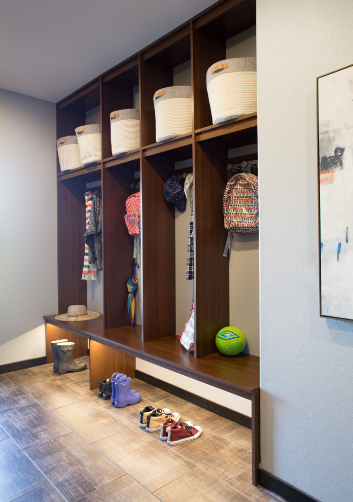 Inspiration pour une entrée minimaliste de taille moyenne avec un vestiaire, un mur bleu, un sol en ardoise et un sol marron.