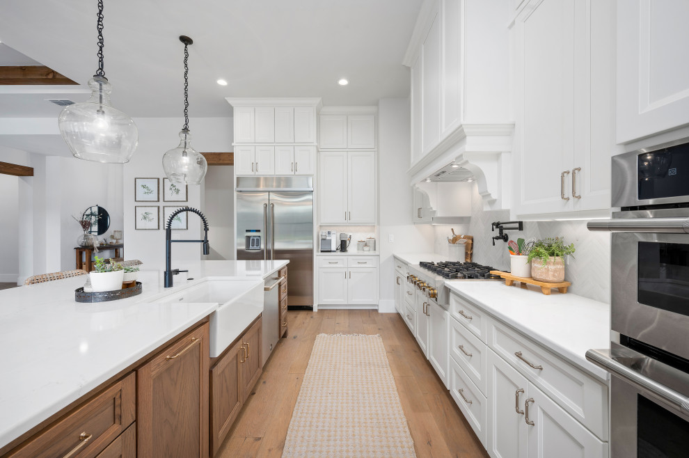 Transitional kitchen photo in Austin with a farmhouse sink, shaker cabinets, yellow cabinets, quartzite countertops, white backsplash, stainless steel appliances, an island and white countertops