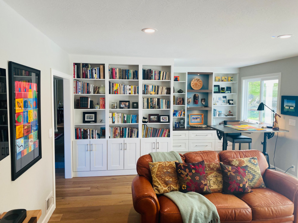 This is an example of a large country enclosed family room in San Francisco with a library, white walls, light hardwood floors, a standard fireplace and a wall-mounted tv.