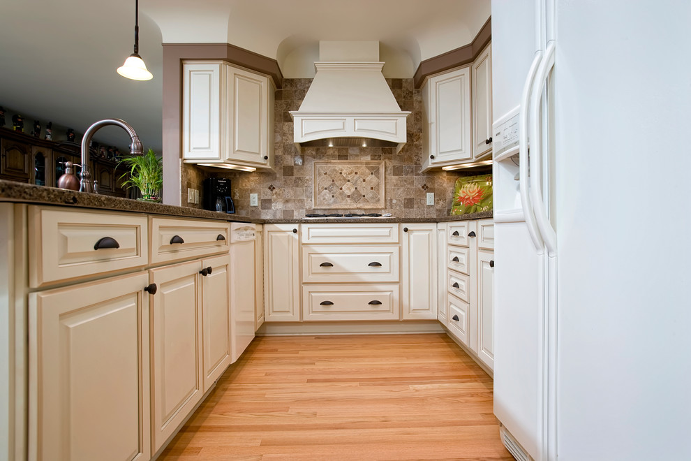 Inspiration for a mid-sized traditional l-shaped open plan kitchen in Detroit with an undermount sink, raised-panel cabinets, white cabinets, granite benchtops, brown splashback, stone tile splashback, white appliances, light hardwood floors, a peninsula and brown floor.