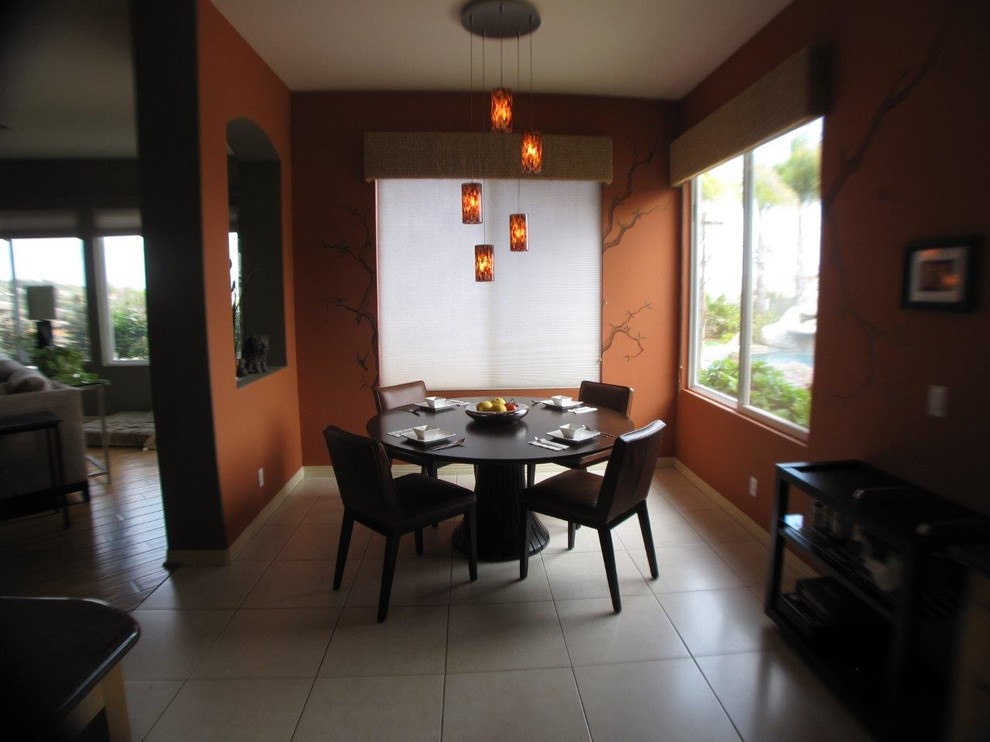 This is an example of a mid-sized contemporary open plan dining in San Diego with orange walls and porcelain floors.