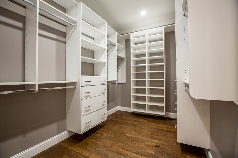 This is an example of a mid-sized country walk-in wardrobe in Other with white cabinets, medium hardwood floors and brown floor.