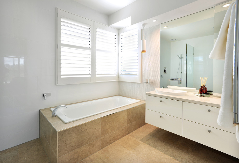 Large contemporary master bathroom in Melbourne with furniture-like cabinets, white cabinets, a drop-in tub, an open shower, a wall-mount toilet, white tile, ceramic tile, white walls, porcelain floors, a vessel sink, engineered quartz benchtops, beige floor and an open shower.