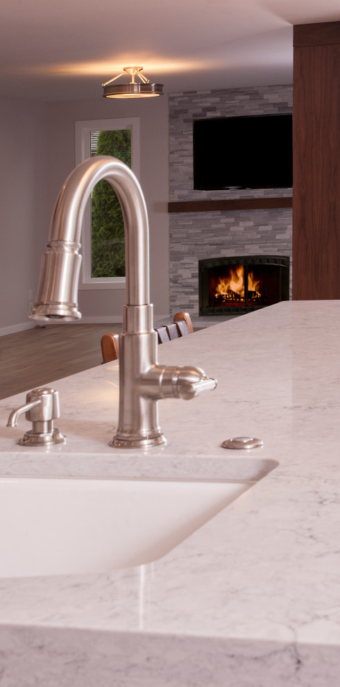 Example of a large transitional u-shaped light wood floor and brown floor eat-in kitchen design in Seattle with a farmhouse sink, dark wood cabinets, white backsplash, subway tile backsplash, stainless steel appliances, an island and white countertops